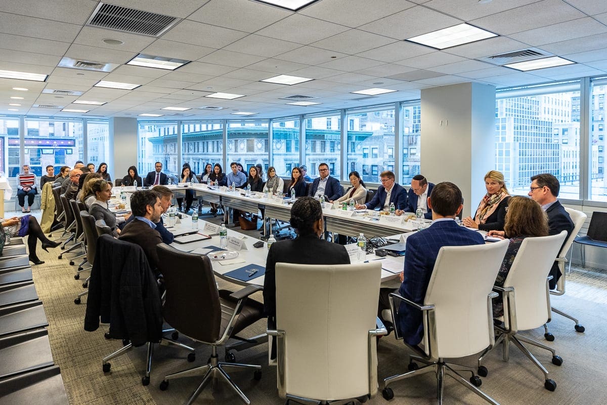 Men and women sit at a conference table discussing environmental, social and governance, or ESG, frameworks at an GSup forum.